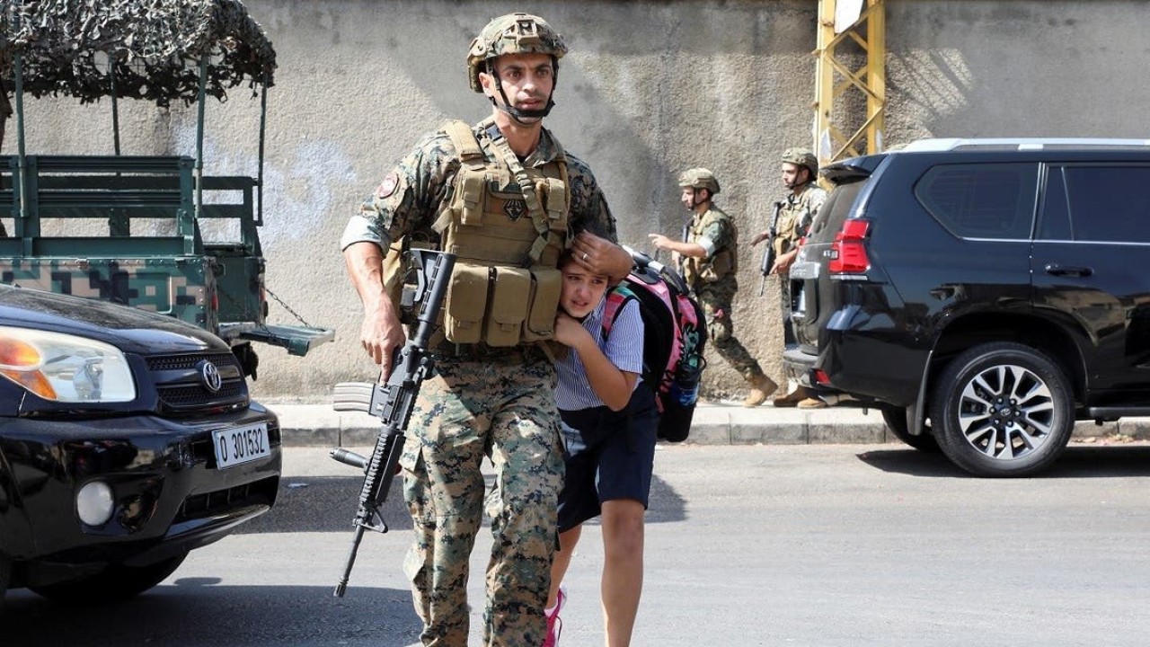 Tentara membantu seorang siswi pergi ke orang tuanya, setelah baku tembak meletus di Beirut, Lebanon, Kamis (14/10/2021). (Reuters)