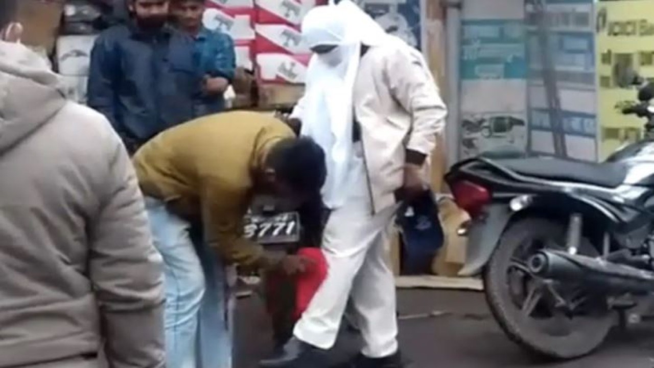 Seorang pemuda sedang membersihkan celana polwan yang terkena kotoran. (India Times)