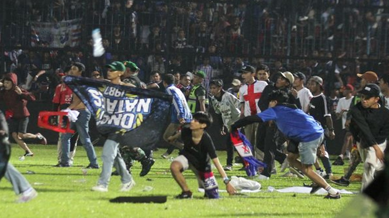 Suporter Arema FC memasuki lapangan setelah tim yang didukungnya kalah dari Persebaya dalam pertandingan sepak bola Liga 1 di Stadion Kanjuruhan, Malang, Sabtu (1/10/2022). (Foto: Antara)