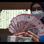 Petugas perbankan menunjukkan uang dolar AS dan uang rupiah, Jakarta, Selasa (31/1/2023). (ANTARA FOTO/Reno Esnir/tom/aa)-1692943231