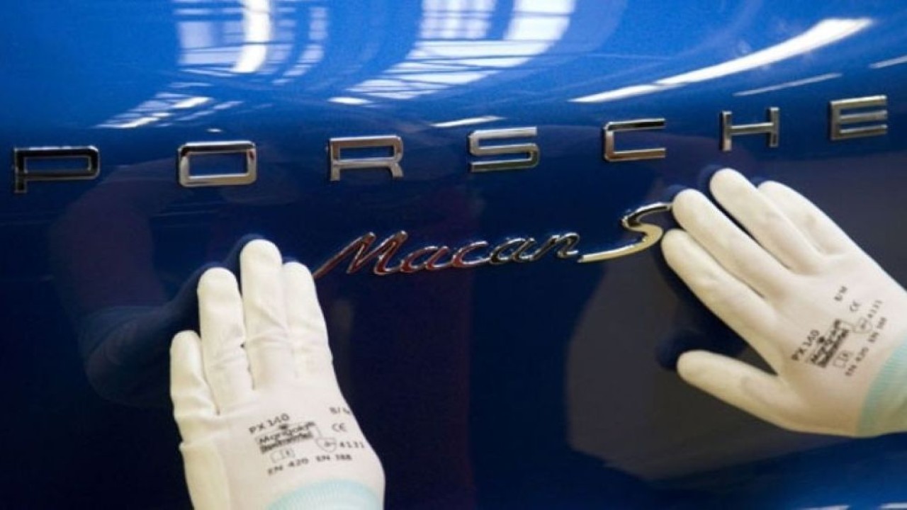 Seorang pekerja memberikan emblem pada mobil Porsche Macan saat diproduksi di pabrik Leipzig di Jerman Timur. (Foto: Dok/Tobias Schwarz/Reuters)