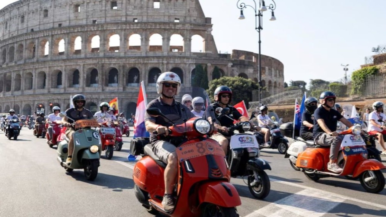 Para pengendara Vespa berkendara melewati Colosseum pada hari terakhir "Vespa Roma 2026 - 80 Tahun Sebuah Ikon", sebuah pertemuan global selama empat hari yang menandai ulang tahun ke-80 merek skuter ikonik Italia, di Roma, Italia, 27 Juni 2026. (Foto: Dok/Remo Casilli/Reuters)